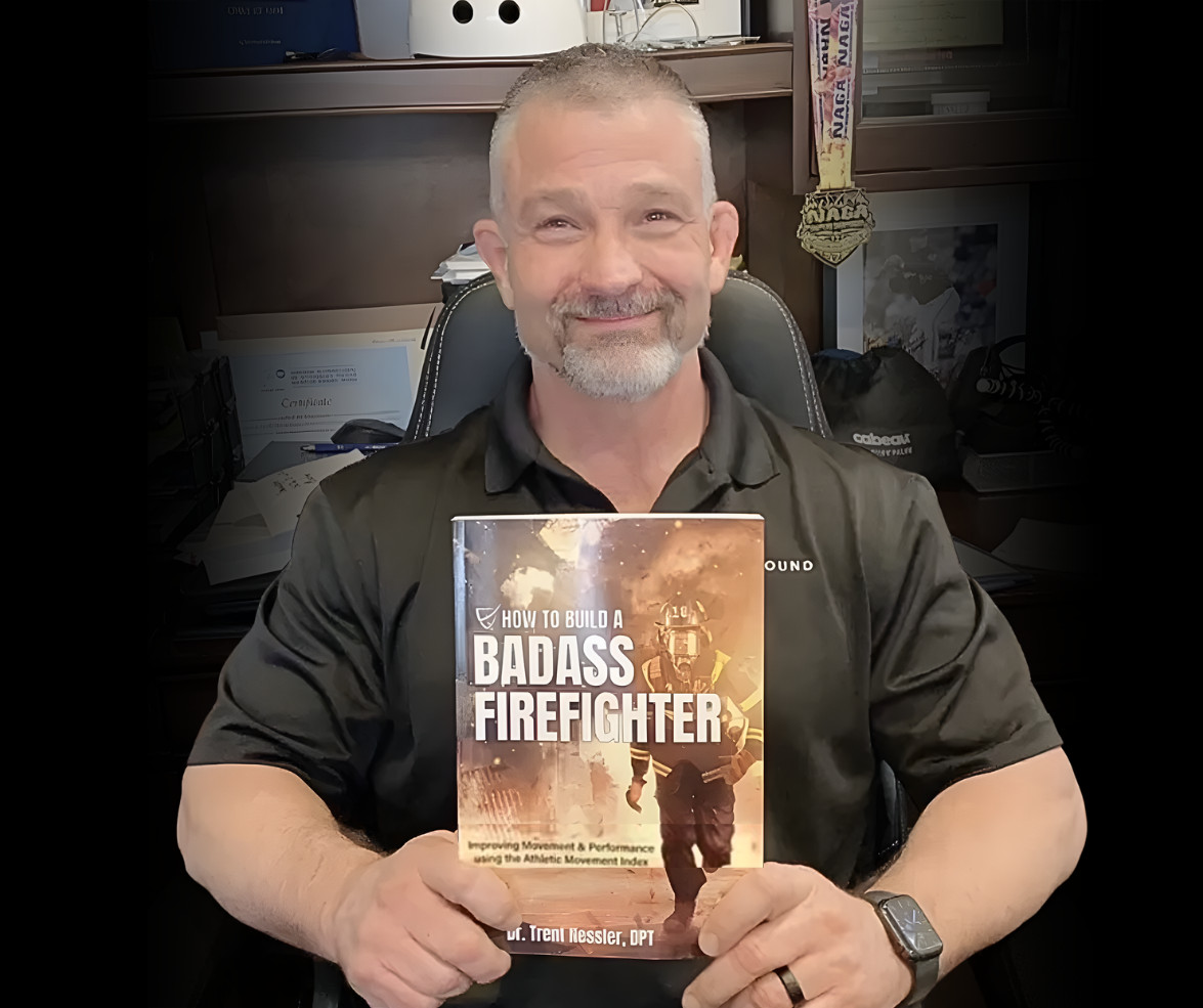 Dr. Trent Nessler holds his book How to Build a Badass Firefighter in his office.